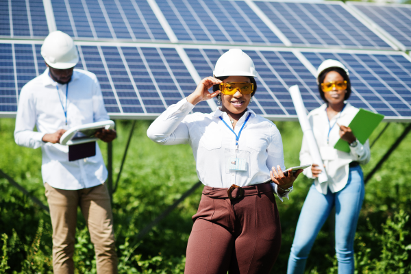 three employees next to solar panels